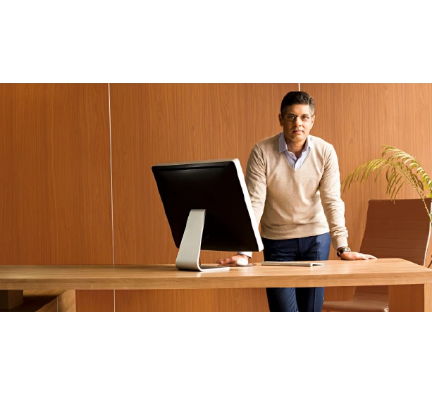 Businessman standing at desk with computer in moden wood-paneled office