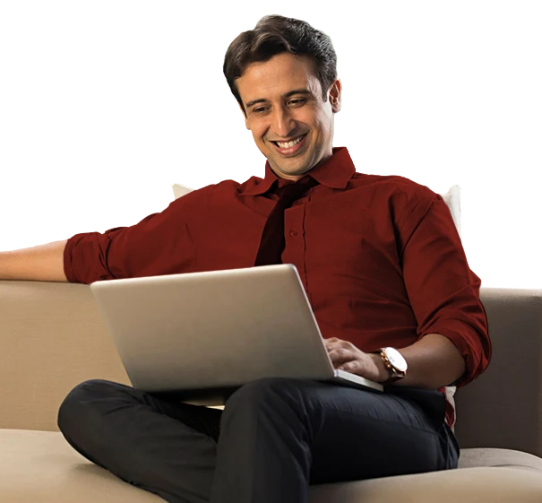 Man sitting on sofa using laptop against orange background.