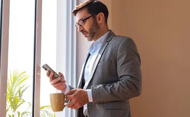 NRI Premium Programme banner with businessman using smartphone.