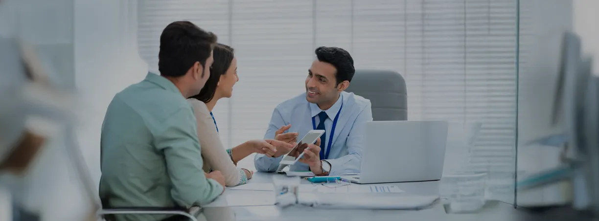 Bank advisor discussing financial plans with couple in office.