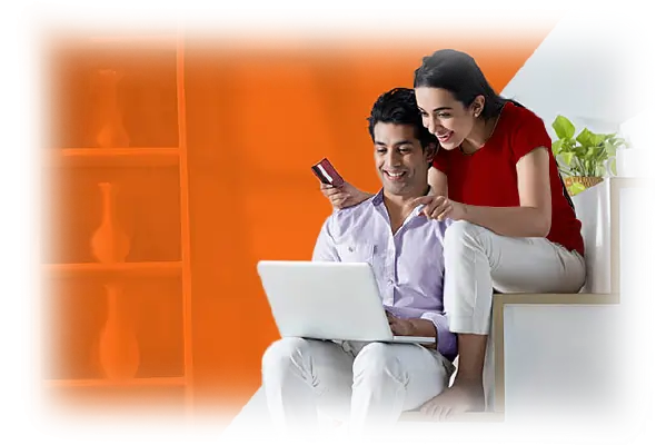 Couple sitting on a sofa using laptop and smartphone for online banking.