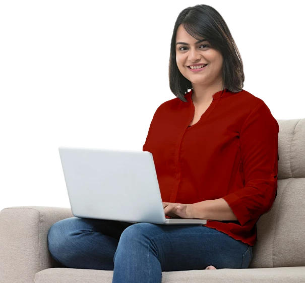 Smiling woman in a red top sitting on a couch, using a laptop 