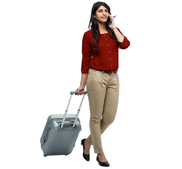 Woman in a red top pulling a suitcase while taking on her phone 