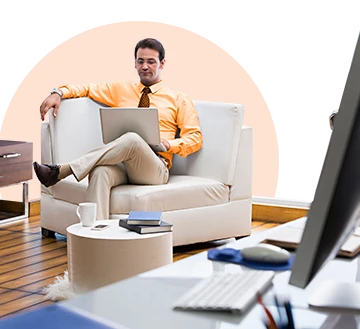 Man relaxing in armchair using laptop at home office desk