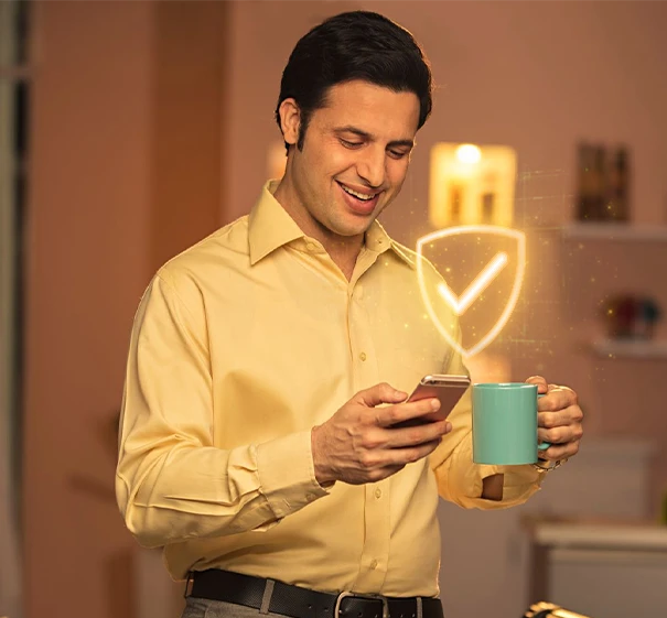 Man checking smartphone with security shield icon beside him.